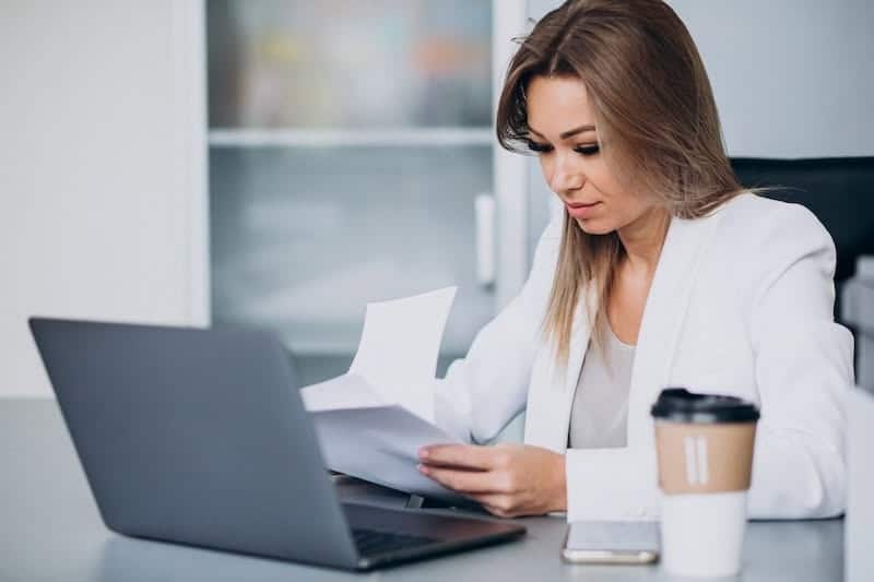 Beautiful business woman working on computer in office and drinking coffee