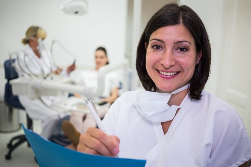 Portrait of female dentist writing report in dental clinic